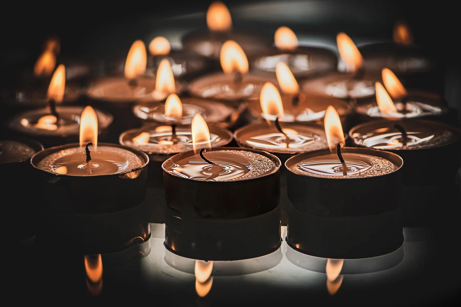 Rows of lit tea lights in a darkened meditation space