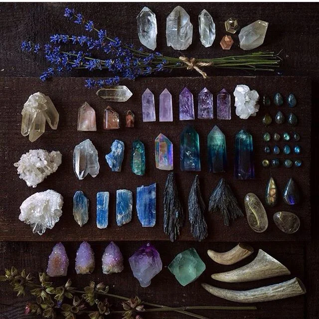 A collection of raw and polished crystals laid out on dark wood