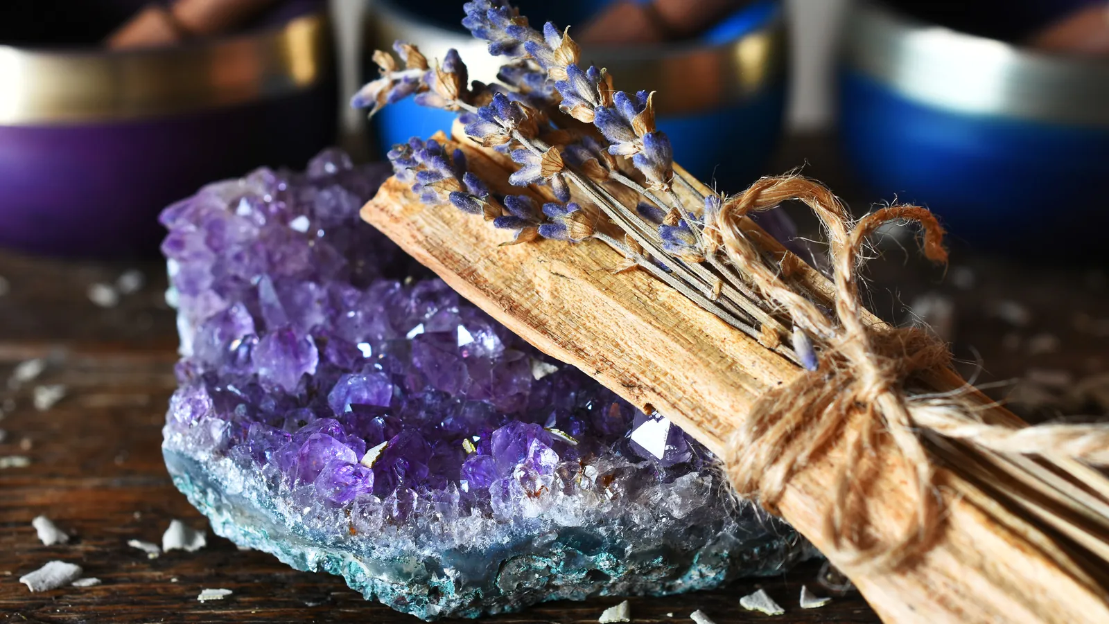 An amethyst cluster with a stick of palo santo and dried lavender