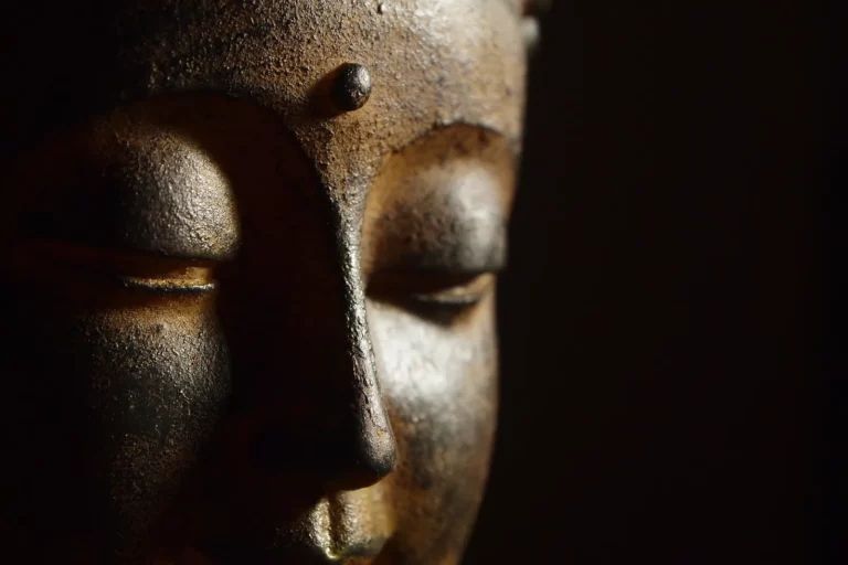 The face of a Buddha statue lit softly from one side