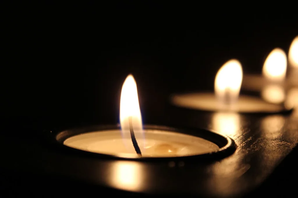 A row of tealight candles burning in the dark