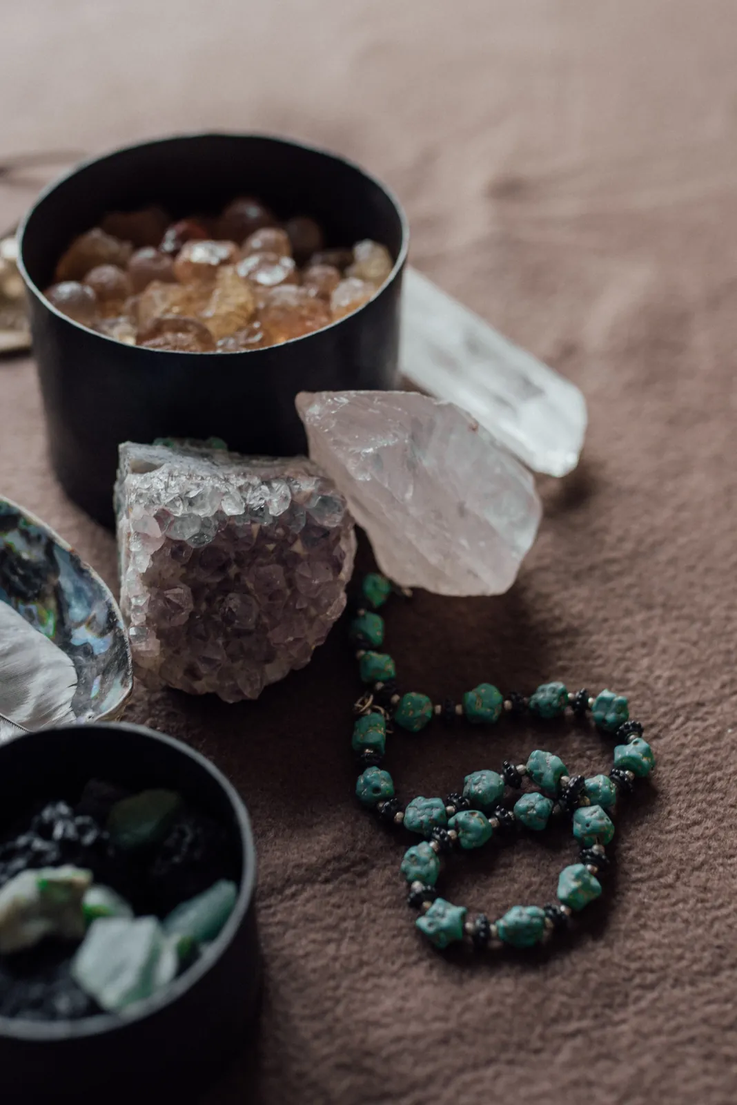 Raw crystals in small tins beside a turquoise mala